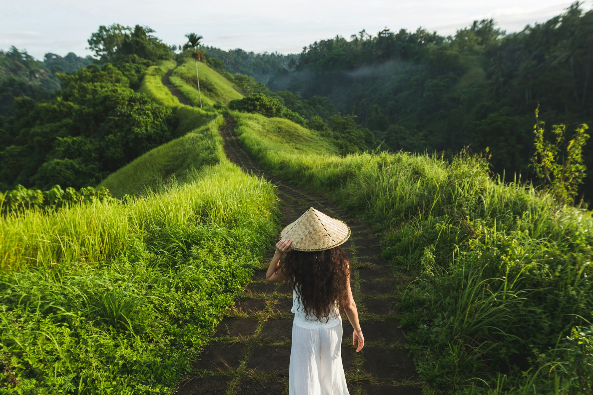 Young beautiful woman walking on Campuhan Ridge way of artists, in Bali, Ubud